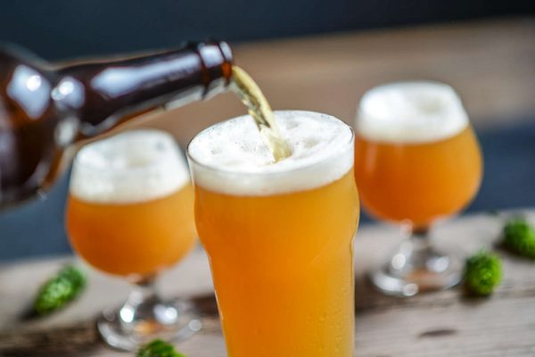 hazy, golden beer being poured from bottle