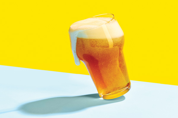 Tipped glass with beer foam spilling over