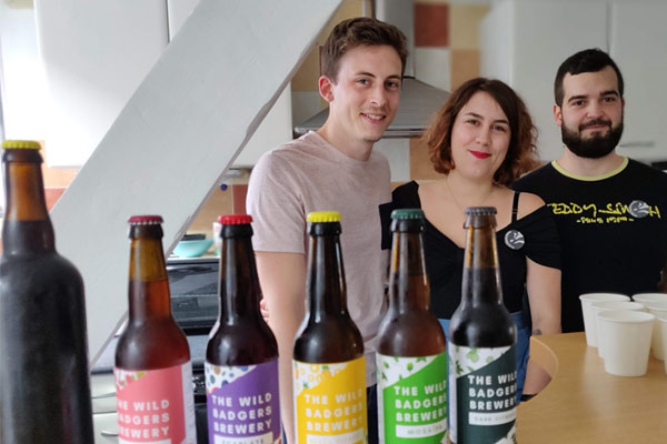 three people posing with homebrew beer bottles