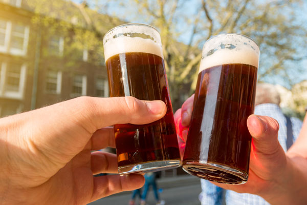 two people cheersing with glasses of copper-colored altbier